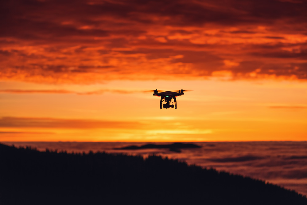 Eine private Drohne fliegt dem Sonnenuntergang entgegen